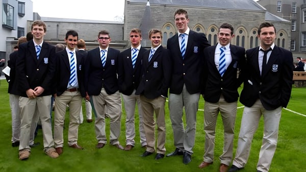 Eine Gruppe Schüler des Blackrock College steht auf einer Grasfläche vor einem Steingebäude.