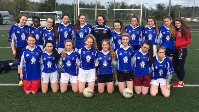 Eine Gruppe junger Fußballspielerinnen in blauen Trikots posiert auf dem Fußballfeld der Blackwater Community School.