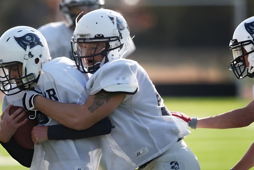 Eine Gruppe von Footballspielern in weißen Uniformen steht auf einem Rasenfeld auf dem Gelände der Blair Academy.
