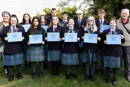 Eine Gruppe Schüler des Blue Mountain College steht zusammen mit Zertifikaten vor einem Gebäude im Freien.