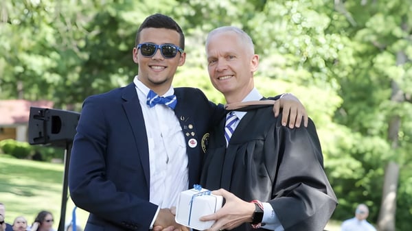 Zwei Personen stehen in einem parkähnlichen Bereich auf dem Gelände der Blue Ridge School mit grüner Vegetation im Hintergrund.