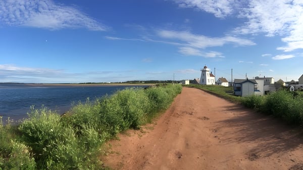 Ein Strandweg mit Blick auf einen Leuchtturm unter blauem Himmel auf dem Gelände der Bluefield High School.