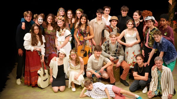 Eine große Gruppe von Schülern der Blundells School versammelt sich auf der Bühne in verschiedenen bunten Outfits.