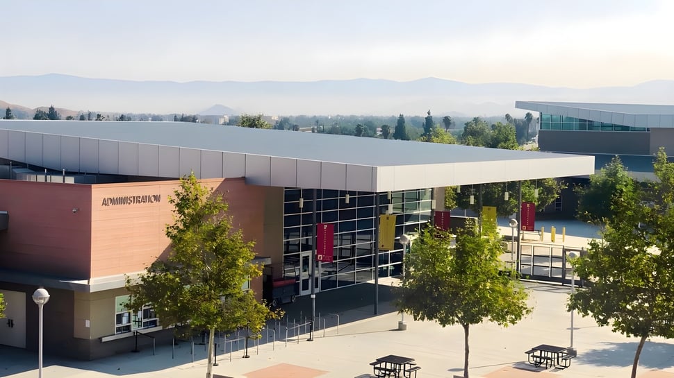 Das moderne mehrstöckige Gebäude mit Glaswänden im Bonneville Joint School District ist von Bäumen umgeben und zeigt die Bergkulisse im Hintergrund.