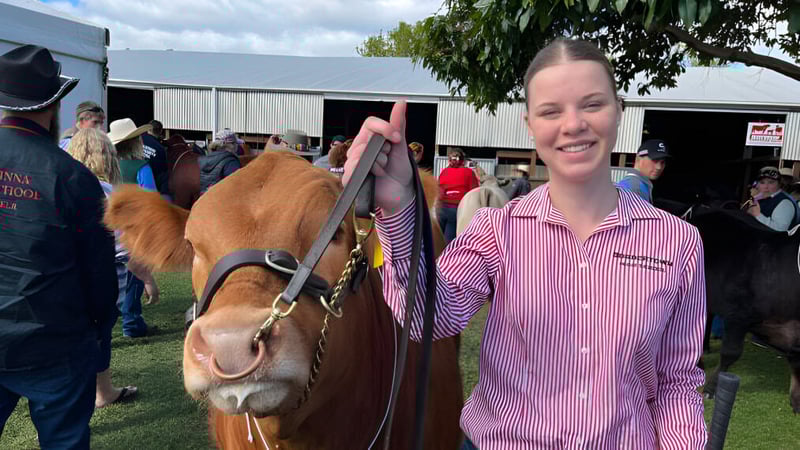 Eine junge Frau steht lächelnd vor einer Gruppe von Pferden auf dem Außengelände der Bordertown High School.