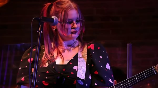 Eine Schülerin des Boston College spielt Gitarre und singt auf einer bunt beleuchteten Bühne.