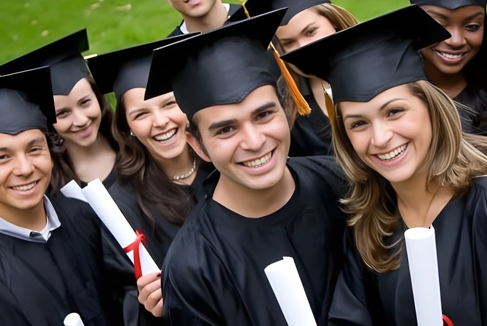 Absolventinnen und Absolventen des Boston College stehen gemeinsam im Freien in ihren schwarzen Talaren und Hüten.