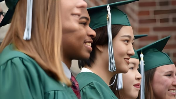 Absolventen der Boston Trinity Academy stehen in grünen Talaren und Mützen zusammen und lächeln.