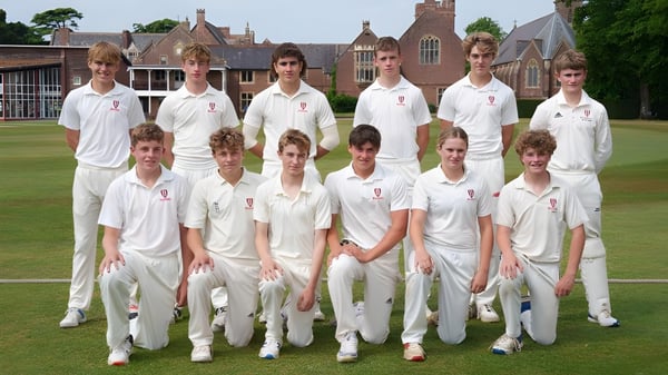 Eine Gruppe Schüler in Cricket-Uniformen posiert auf einem Rasenfeld vor einem historischen Gebäude auf dem Gelände des Bosworth Independent College.