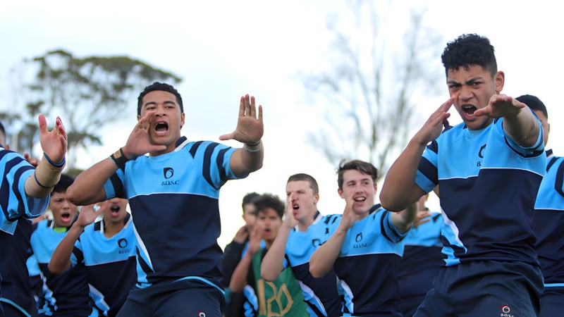 Eine Gruppe Schüler des Botany Downs Secondary College feiert auf dem Sportplatz in ihren blauen Sportuniformen.