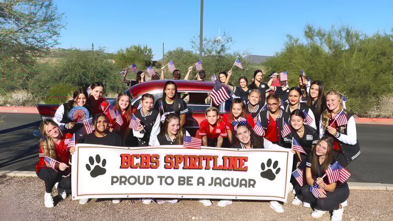 Eine Gruppe von Schülerinnen und Schülern der Boulder Creek High School posiert vor einem roten Fahrzeug und einem Banner der Spirit Line.