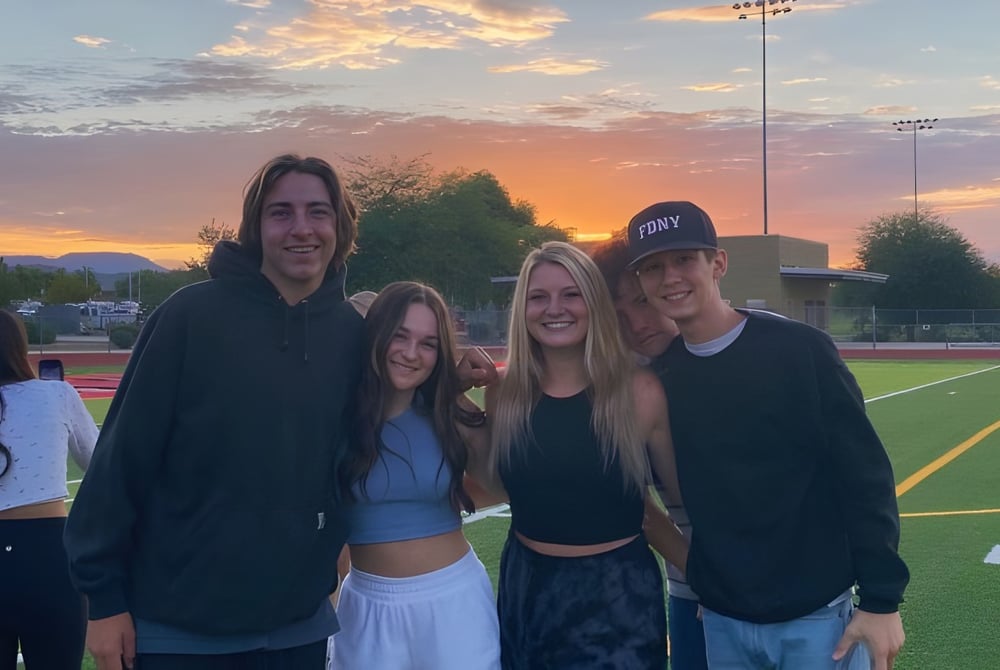 Vier Schülerinnen und Schüler der Boulder Creek High School stehen gemeinsam auf dem Sportfeld bei Sonnenuntergang.
