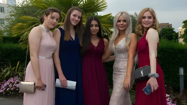 Fünf Schülerinnen der Bournemouth Collegiate School posieren in formeller Kleidung vor tropischer Pflanzenkulisse.