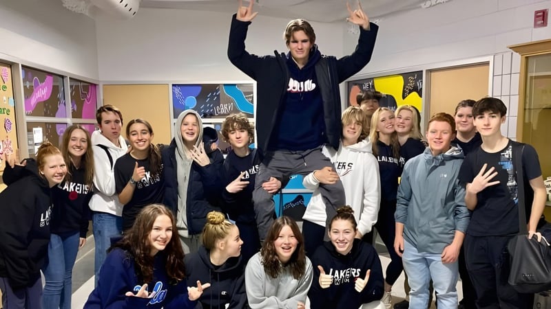 Eine Gruppe Schülerinnen und Schüler der Bracebridge and Muskoka Lakes Secondary School posiert in einem Klassenraum mit bunten Postern an der Wand.