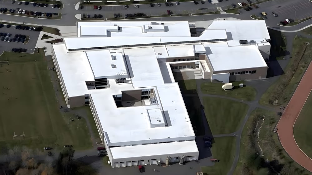 Das moderne mehrstöckige Schulgebäude der Bracebridge and Muskoka Lakes Secondary School mit Parkplatz und Grünflächen im Hintergrund.