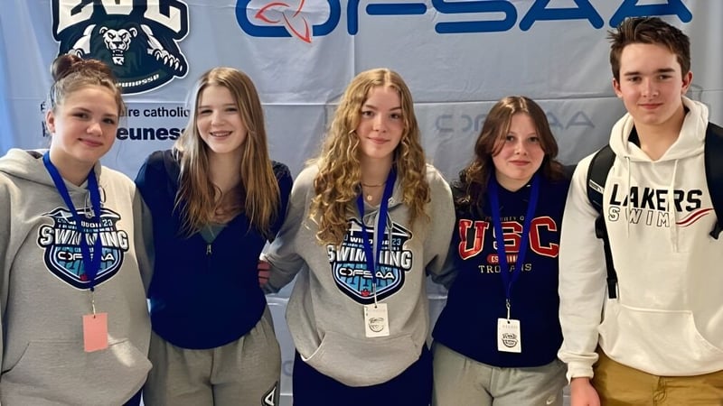 Eine Gruppe von Schülern der Bracebridge and Muskoka Lakes Secondary School steht vor einem Banner mit dem Logo einer Sportorganisation.