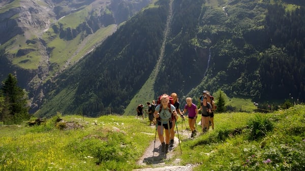 Eine Gruppe von Schülern des Bradfield College wandert durch eine bergige Landschaft mit dichten Wäldern im Hintergrund.