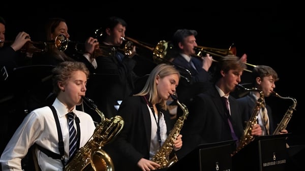 Eine Gruppe von Musikern des Bradfield College spielt auf der Bühne mit Blech- und Holzblasinstrumenten.