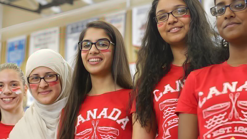Eine Gruppe junger Frauen in roten Canada-Shirts posiert gemeinsam im Innenraum der Bradford District High School.
