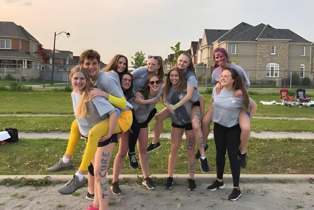 Eine Gruppe Schülerinnen steht auf einer Wiese vor Wohngebäuden auf dem Gelände der Bradford District High School.