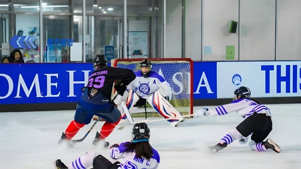 Schülerinnen und Schüler von Branksome Hall Asia spielen ein Eishockeyspiel in einer Halle mit Werbetafeln im Hintergrund.