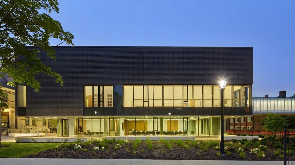 Das mehrstöckige moderne Gebäude von Branksome Hall steht abends beleuchtet in einer begrünten Umgebung.