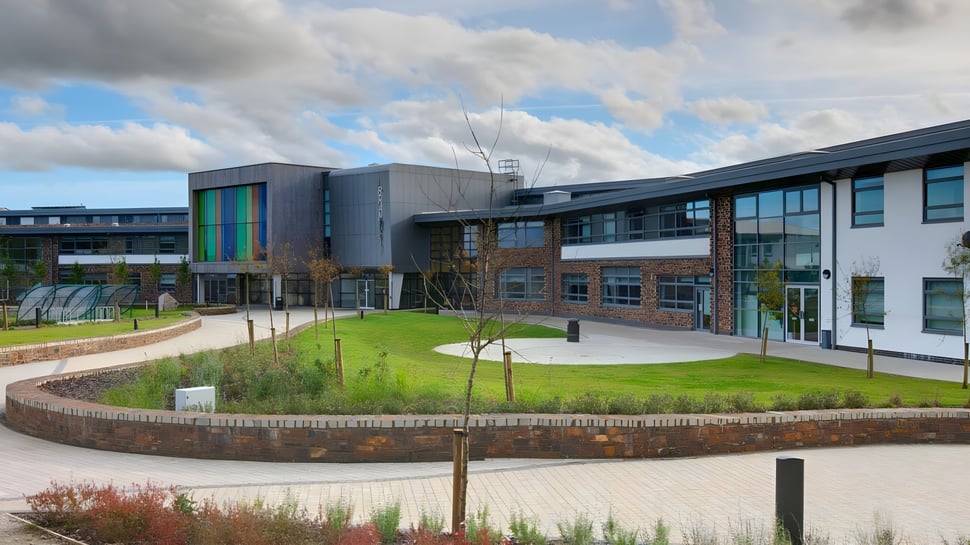 Das moderne mehrstöckige Gebäude der Brannel School mit einem grasbewachsenen Innenhof und gepflasterten Wegen im Vordergrund.