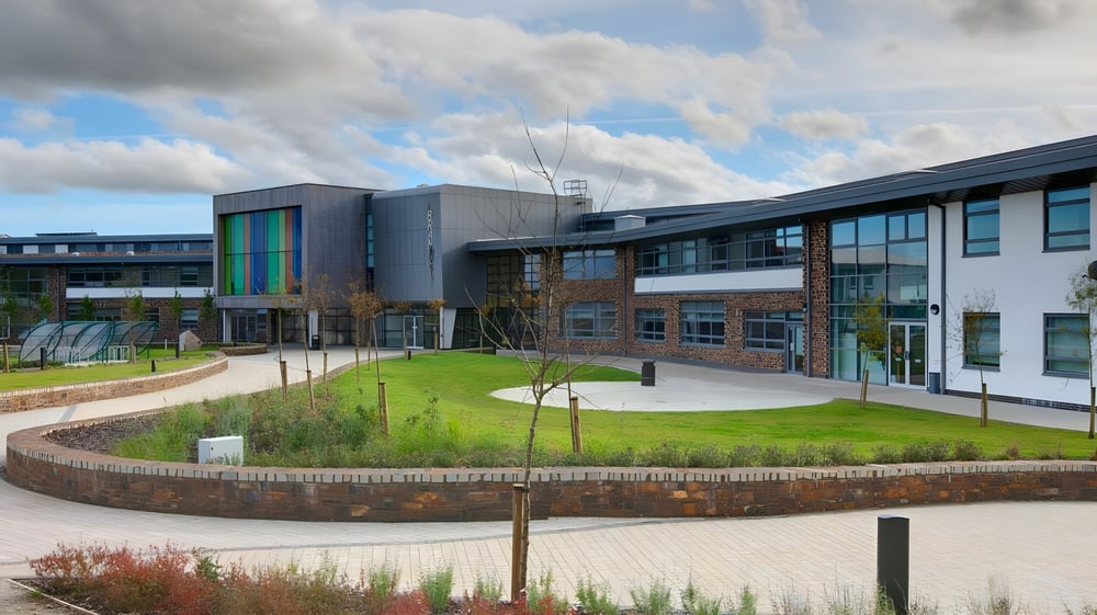 Das moderne mehrstöckige Gebäude der Brannel School mit einem grasbewachsenen Innenhof und gepflasterten Wegen im Vordergrund.