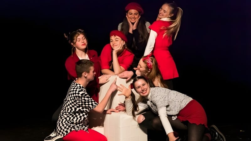 Eine Gruppe von Schülerinnen der Brannel School posiert in roten, schwarzen und weißen Outfits in einem dunklen Raum.