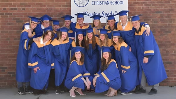 Eine Gruppe von Absolventinnen und Absolventen der Brant Christian School posiert vor einem Schulbanner.