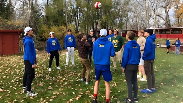 Eine Gruppe von Schülerinnen und Schülern der Brant Christian School trägt blaue Uniformen und steht in einem bewaldeten Gebiet mit Laub auf dem Boden.