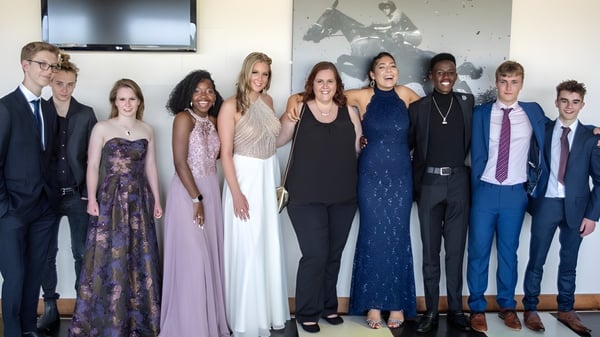 Eine Gruppe von Personen in formeller Kleidung steht vor einer dekorierten Wand auf dem Gelände der Bredon School.