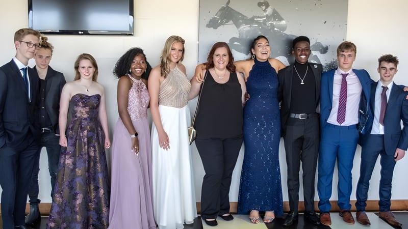 Eine Gruppe von Personen in formeller Kleidung steht vor einer Wand mit Kunstwerken auf dem Campus der Bredon School.