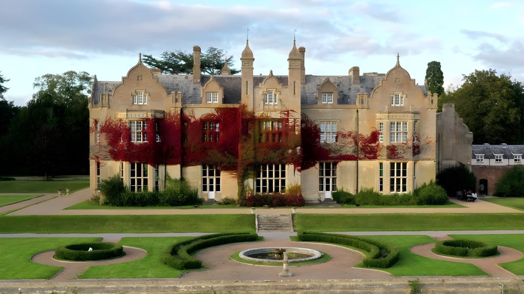Das Schloss mit Türmen und Garten auf dem Gelände der Bredon School ist umgeben von einem gepflegten Rundweg und Zierhecken.