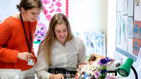 Zwei Schülerinnen der Bredon School stehen in einem Raum mit bunter Kunst an den Wänden.