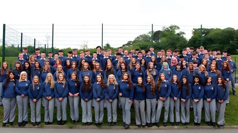 Eine große Gruppe von Schülerinnen und Schülern des Breifne College steht zusammen im Freien vor einem Hintergrund aus Bäumen und Stromleitungen.