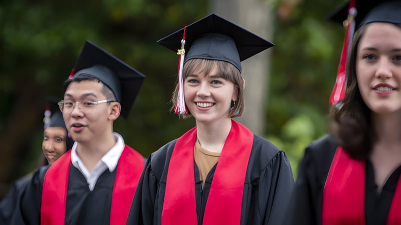 Absolventinnen und Absolventen der Brentwood College School in akademischer Kleidung vor einem natürlichen Hintergrund.