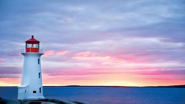 Ein Leuchtturm steht bei Sonnenuntergang am Wasser in der Nähe des Brentwood College School.