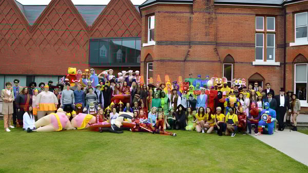 Eine Gruppe kostümierter Schülerinnen und Schüler versammelt sich vor dem historischen Backsteingebäude der Brentwood School.