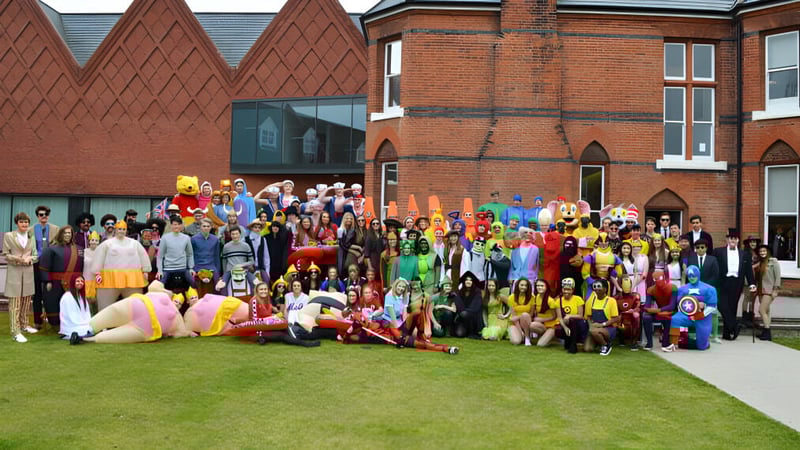Eine Gruppe kostümierter Schülerinnen und Schüler versammelt sich vor dem historischen Backsteingebäude der Brentwood School.