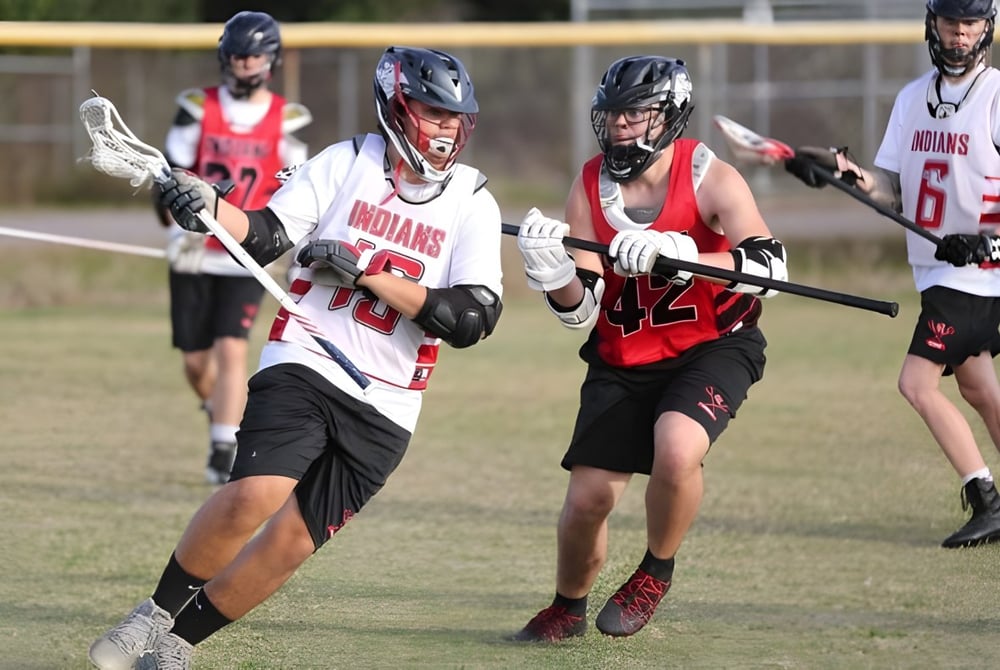 Eine Gruppe von Lacrosse-Spielern in roten und weißen Trikots spielt auf dem Spielfeld der Brevard County Public Schools.