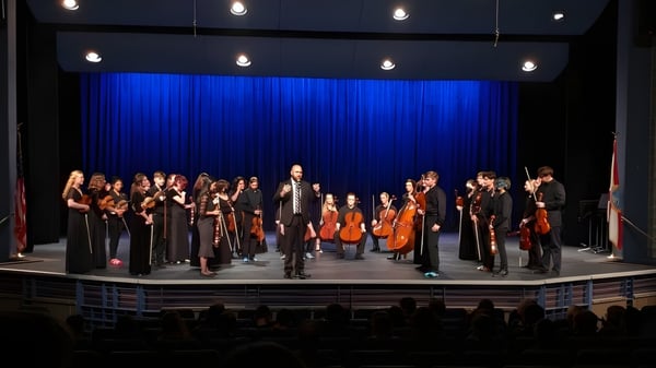 Ein großes Orchester der Brevard County Public Schools tritt auf einer Bühne mit blauem Vorhang und Scheinwerfern auf.