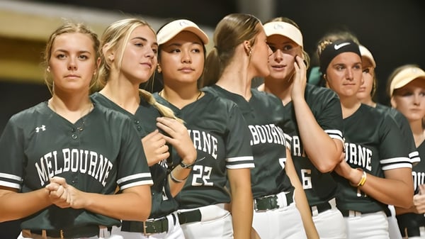 Eine Gruppe weiblicher Athletinnen im einheitlichen grünen und weißen Trikot steht auf einem Softballfeld bei Brevard County Public Schools.