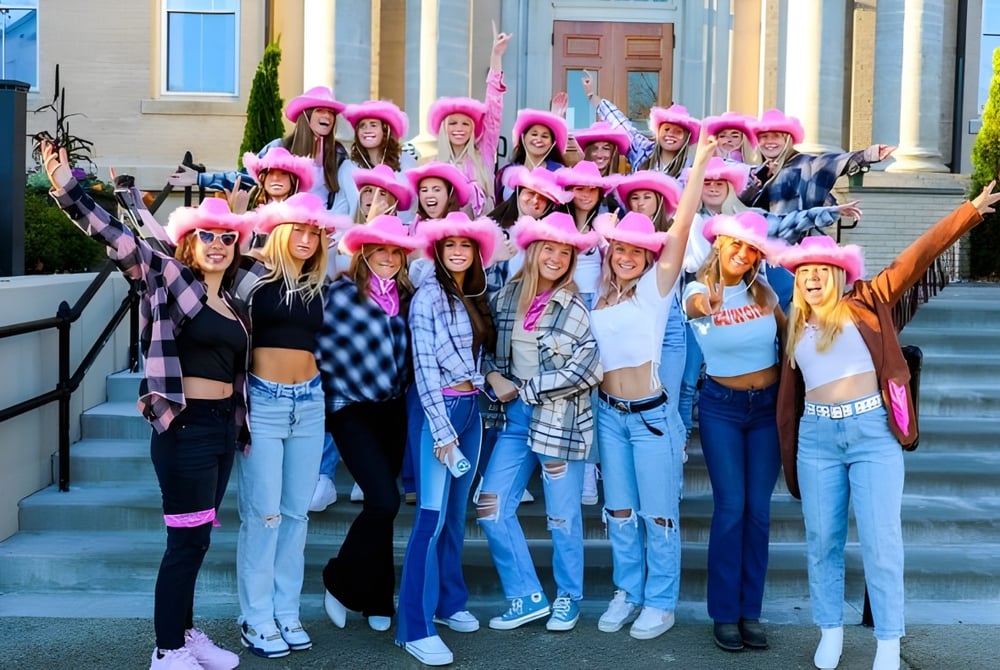 Eine Gruppe Schülerinnen der Brewster Academy sitzt auf den Treppen vor einem Gebäude mit klassischer Architektur.