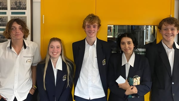 Fünf Schülerinnen und Schüler posieren gemeinsam vor einer gelben Wand auf dem Gelände der Bribie Island State High School.