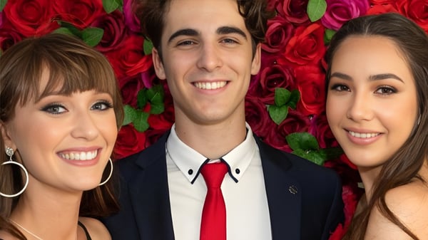 Drei Schülerinnen und Schüler vor einem Hintergrund mit leuchtend roten Rosen auf dem Gelände der Bribie Island State High School.