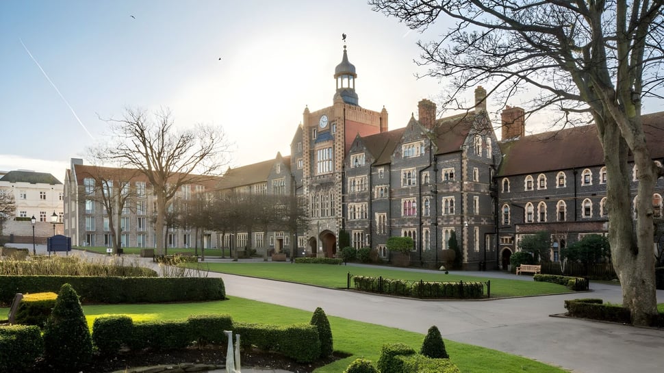 Der Innenhof von Brighton College zeigt einen gepflegten Rasen und historische Gebäude bei klarem Himmel.