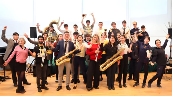 Eine Gruppe von Schülern und Musikern des Brighton College versammelt sich mit ihren Instrumenten in einem Proberaum.