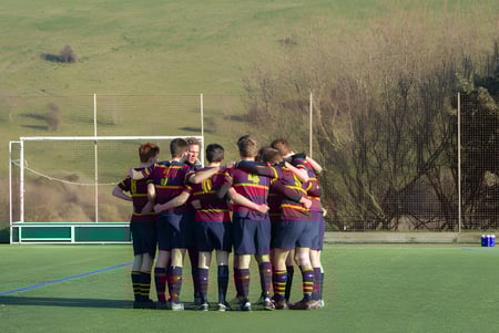 Eine Gruppe von Schülerinnen und Schülern steht auf dem Sportfeld des Brighton College umgeben von einer grünen Landschaft.