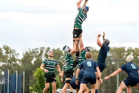 Eine Gruppe Rugby spielender Schüler des Brisbane Boys' College während eines Spiels mit einem Spieler, der hochspringt, um den Ball zu fangen.